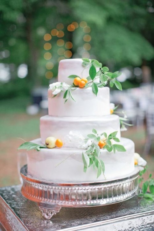 a white textural wedding cake with greenery and kumquats, with white blooms is a great idea for a summer or tropical wedding