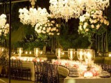 a refined wedding reception with tall candleholders and large crystal chandeliers over it looks beautiful and enchanting