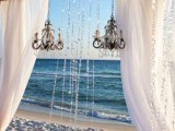 a cute beach wedding arch with chandeliers