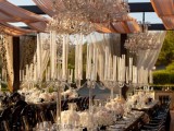 a super exquisite wedding reception space with tall candelabras, white blooms and crystal chandeliers over the space is amazing