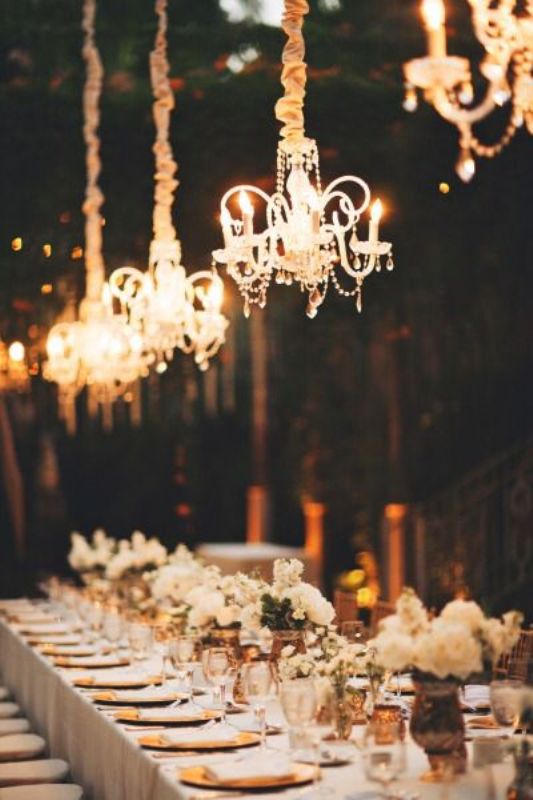 A neutral sophisticated wedding tablescape made more beautiful and chic with crystal chandeliers hanging over the table