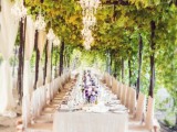 a refined garden wedding reception with vines covering the arches, neutral curtains and chic crystal chandeliers to litght up and cozy up the space