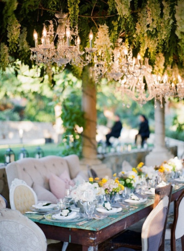 Greenery and floral garlands paired with crystal chandeliers give this wedding reception a chic and refined feel