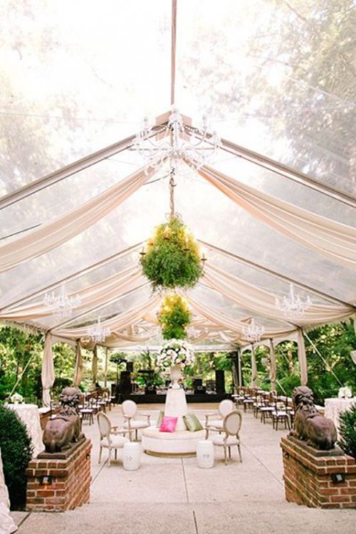 a beautiful tent with greenery arrangements, crystal chandeliers to light up the space and make it more beautiful