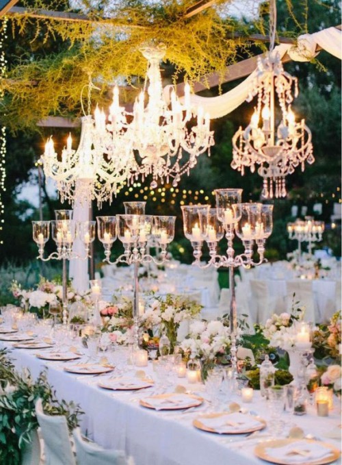 a beautiful wedding tablescape with white florals, tall candelabras, crystal chandeliers is very glam and very refined