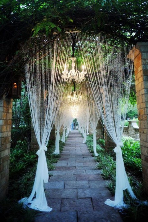 a corridor leading to the venue styled with crystal candles and crystal chandeliers plus greenery is a pretty idea with a magical feel