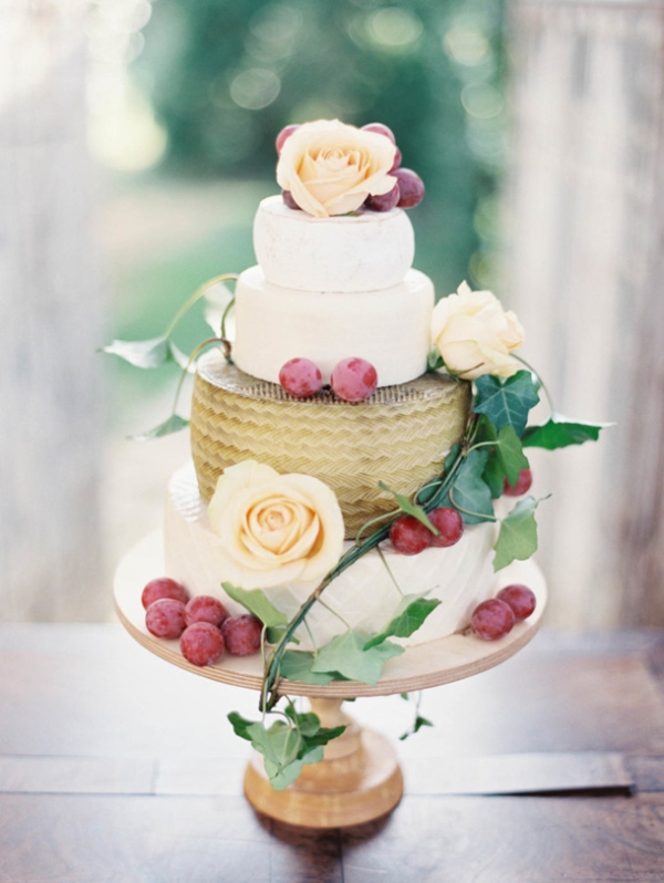 A cheese wheel wedding cake with fresh neutral blooms, berries and greenery is a lovely alternative to a usual wedding cake