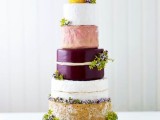 a giant cheese wheel wedding cake topped with fresh greenery is a lovely idea for any wedding