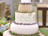 a beautiful stacked cheese wheel wedding cake with fresh greenery and blooms is a lovely idea for a Provence-inspired wedding
