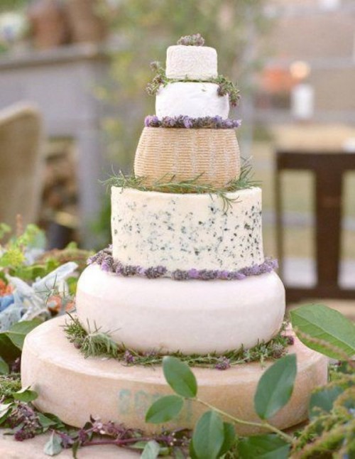 a beautiful stacked cheese wheel wedding cake with fresh greenery and blooms is a lovely idea for a Provence-inspired wedding
