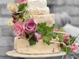 a pretty cheese wheel wedding cake decorated with pink roses and greenery plus some berries is a cool idea for a summer wedding