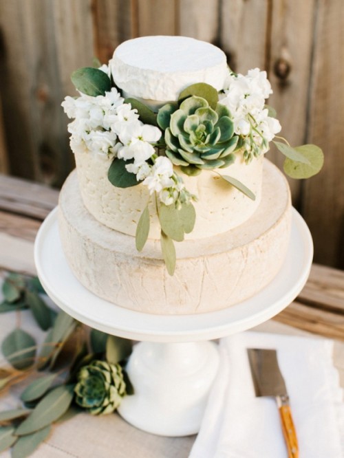 a cheese wheel wedding cake with white blooms, greenery and a succulent is a lovely idea for a spring or summer wedding