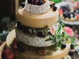 a super creative cheese wheel wedding cake with blackberries, figs, tomatoes and cherries plus some waxflower for decor is a lovely and bold idea