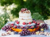 a cheese wheel wedding cake topped with various kinds of fresh berries and fruits is a gorgeous idea for a summer wedding