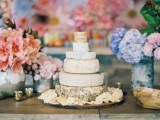 a small yet stylish cheese wheel wedding cake surrounded with pastel blooms is a beautiful idea for a spring or summer wedding