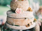 a cheese wheel wedding cake topped with neutral blooms some fresh fruit and berries is a lovely idea for a spring or summer wedding