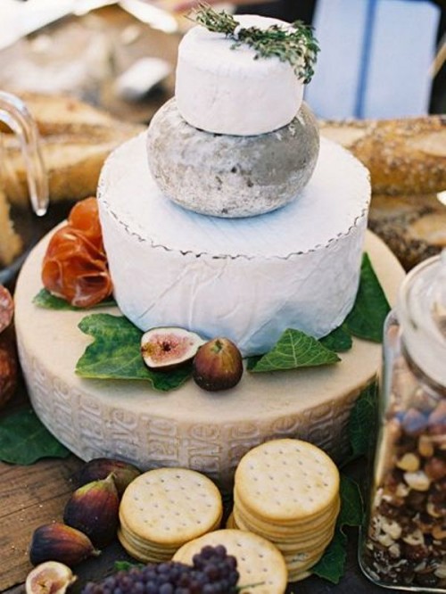a classic cheese wheel wedding cake topped with greenery, figs, fresh herbs and even salami is a lovely idea for an Italian wedding
