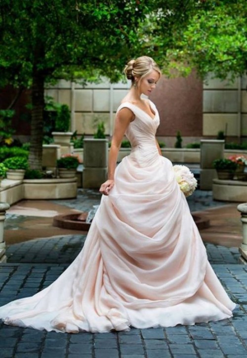 a romantic and refined wedding ballgown in blush, with a draped bodice and a skirt plus thick straps and a train is very exquisite