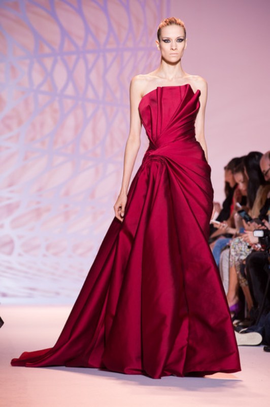 A sculptural burgundy strapless wedding ballgown, a draped bodice and a skirt plus a train is a refined and chic modern outfit for a Valentine bride