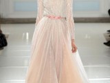 a neutral a-line wedding dress of lace, with long sleeves, a high neckline and a layered and flowy skirt plus a train