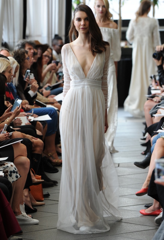 A flowy and airy wedding dress with a draped bodice, long sleeves and a plunging neckline