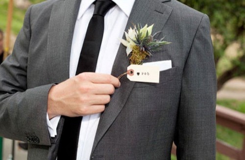 a grey pantsuit, a white shirt and a black skinny tie and a dimensional boutonniere are a cool combo for a wedding