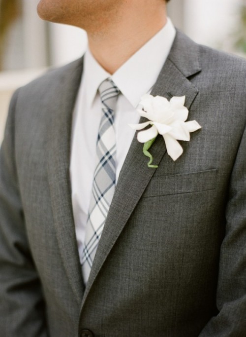 a graphite grey pantsuit, a white shirt, a checked tie and a white flower boutonniere are a chic and cool monochromatic combo