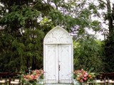 a white vintage double door and bold blooms and greenery lining up the aisle for a vintage-infused wedding in the garden