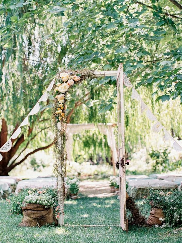 a vintage door decorated with a garland and white blooms plus greenery is a cool wedding backdrop for a vintage wedding