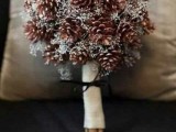 a rustic winter wedding bouquet of pinecones and little white blooms in a burlap wrap is ideal for a rustic bride