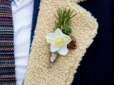 a rustic winter boutonniere of a bloom, evergreens, a pinecone and some twine