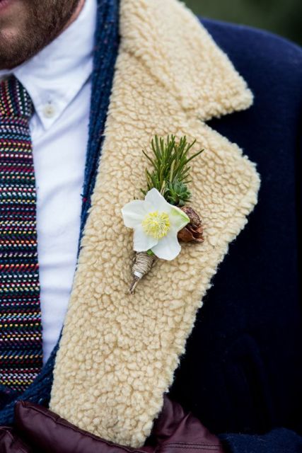 a rustic winter boutonniere of a bloom, evergreens, a pinecone and some twine