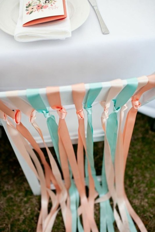 a white chair with peachy and mint fabric ribbons is a chic and fun idea for a spring or summer wedding, looks party-like and cheerful