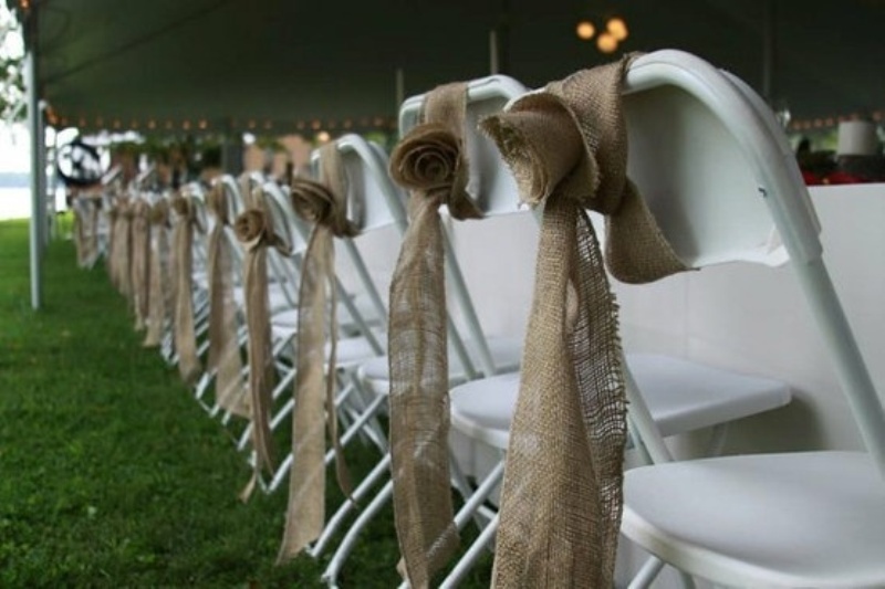 White chairs decorated with burlap roses and ribbons look very rustic and cool and add a cozy feel to the space