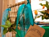 a gold chair accented with greenery and teal ribbons is a lovely and bold solution for a wedding with plenty of color