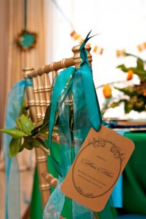 a gold chair accented with greenery and teal ribbons is a lovely and bold solution for a wedding with plenty of color