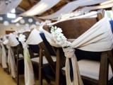 stained wooden chairs with neutral fabric decor and white blooms are great for a rustic wedding