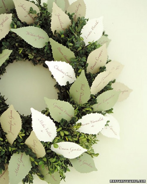 a creative seating chart for a fall or winter wedding - a boxwood wreath with paper cards shaped as leaves