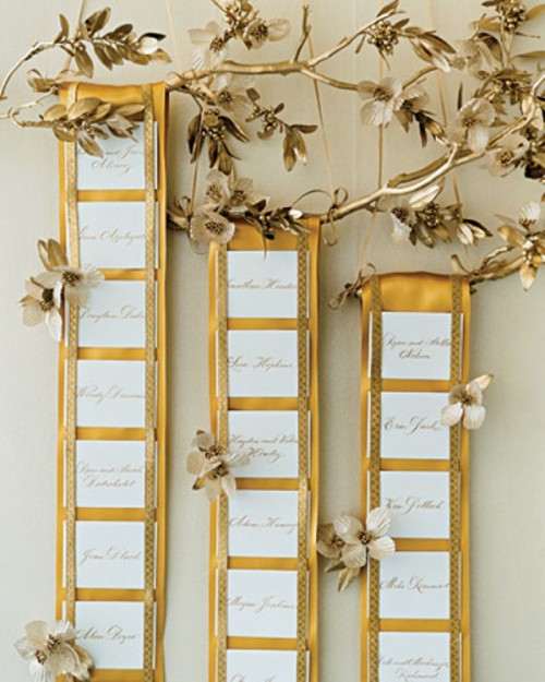 a refined fall seating chart made of mustard fabric straps, elegant cards and a gilded branch with leaves