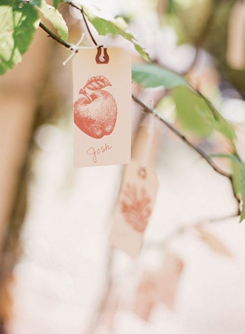 branches with leaves and vintage tags with apple prints are nice escort cards for a fall wedding