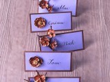 purple framed cards with rust-colored brooches are lovely fall wedding escort cards you can rock at the wedding