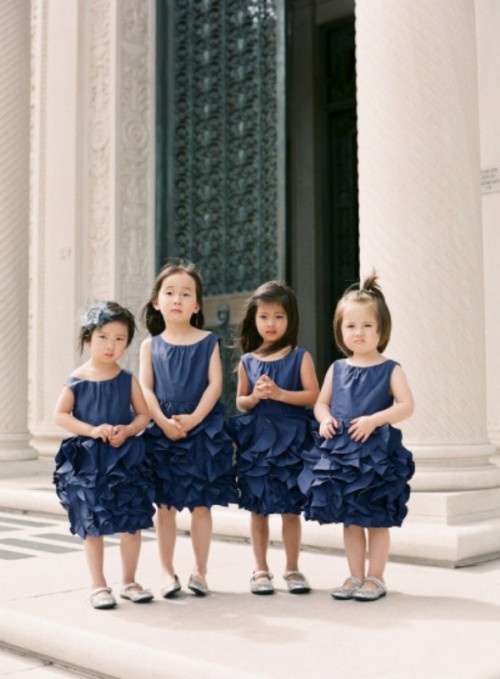flower girls wearing navy dresses with plenty of ruffles and no sleeves look super cute and chic