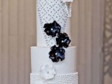 a chic white, silver and navy wedding cake with sugar blooms, beads and patterns