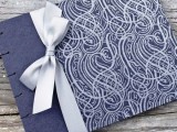 a navy and silver wedding album with a silver bow is a chic idea that matches your wedding color scheme