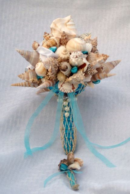 a seashells, starfish and pearl wedding bouquet with a bold blue wrap and ribbons