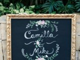 a chalkboard sign with calligraphy and florals and a gold frame is a lovely idea for a modern wedding, it looks elegant and chic