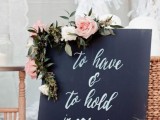 a simple and modern chalkboard sign with white and blush blooms and greenery for a modern wedding