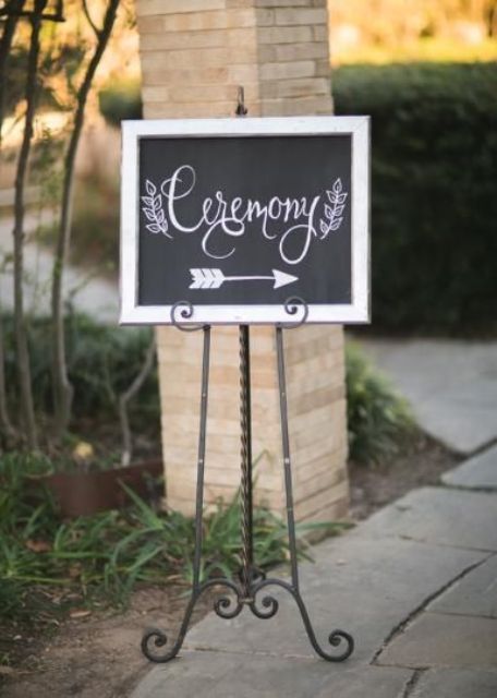 a small chalkboard sign with calligraphy and a white frame placed on metal stands is a lovely idea for a relaxed wedding