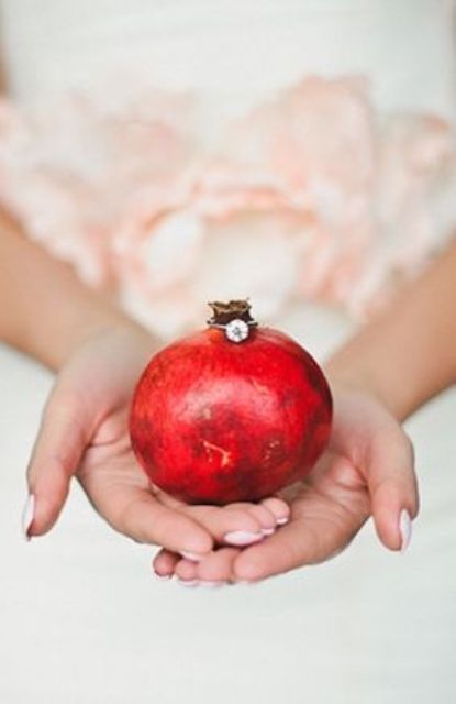 a pomegranate used to show off a wedding ring is a lovely idea for a fall or winter wedding with plenty of color