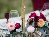 refined fall wedding tablescape with blush and burgundy blooms, greenery, gold candles in gold candleholders and pomegranates is a chic idea